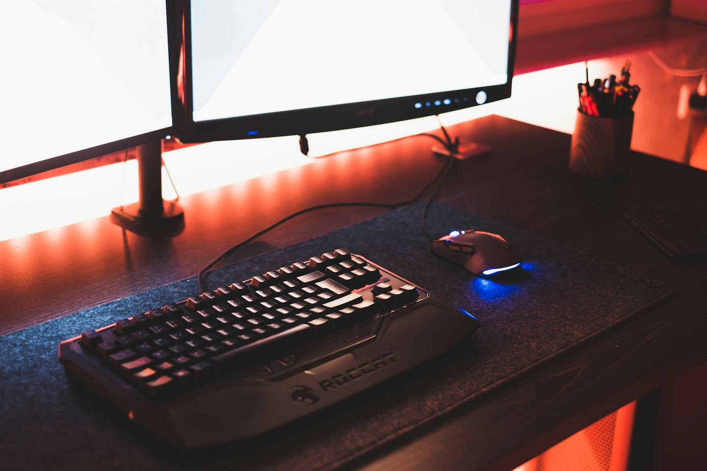 Gaming desk with mechanical keyboard, mouse, and two monitors.